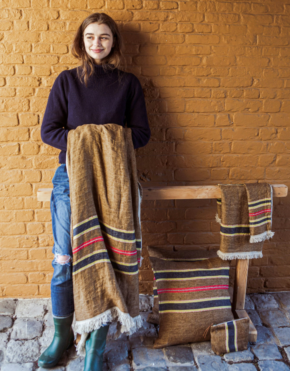 Person holding a woven blanket with a brick wall background