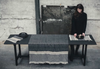 Person arranging items on a table with a textured tablecloth in a minimalistic setting.
