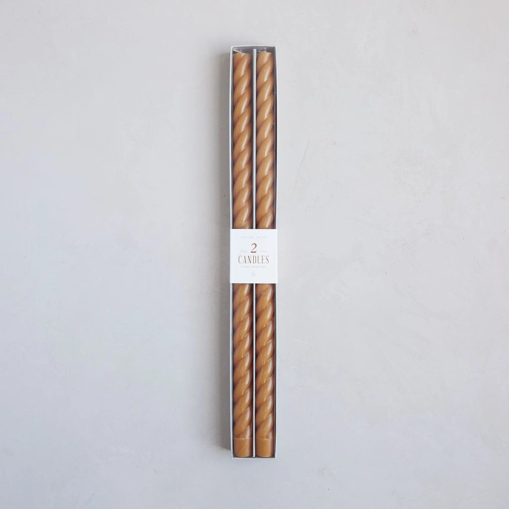 Two tall taper candles in packaging with a label on a light gray background