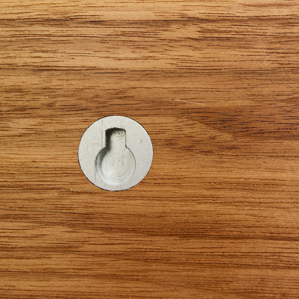 Close-up of a wooden surface with a metal furniture leg socket.