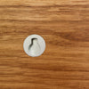 Close-up of a wooden surface with a metal furniture leg socket.