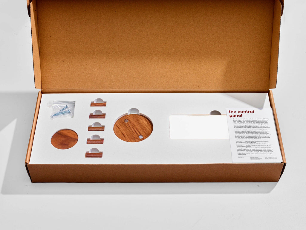 Open box containing wooden control panel components and instructions on a white background