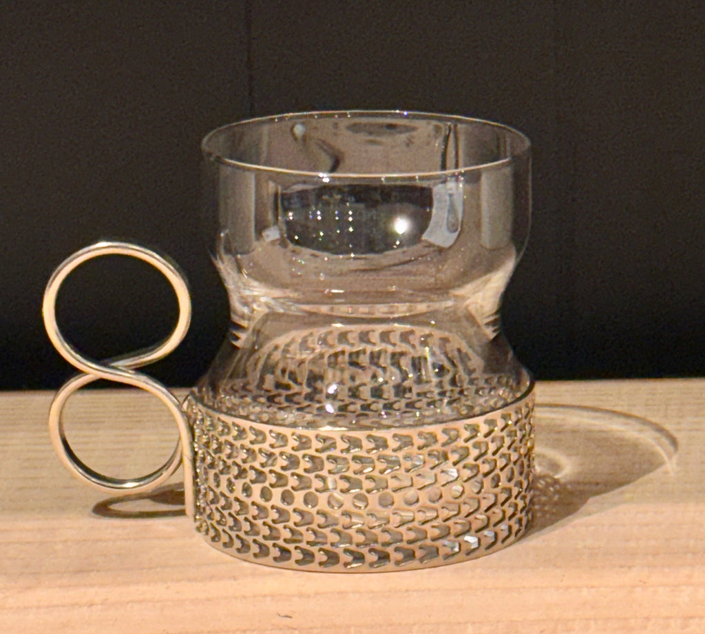 Decorative glass holder with metallic base on a wooden surface