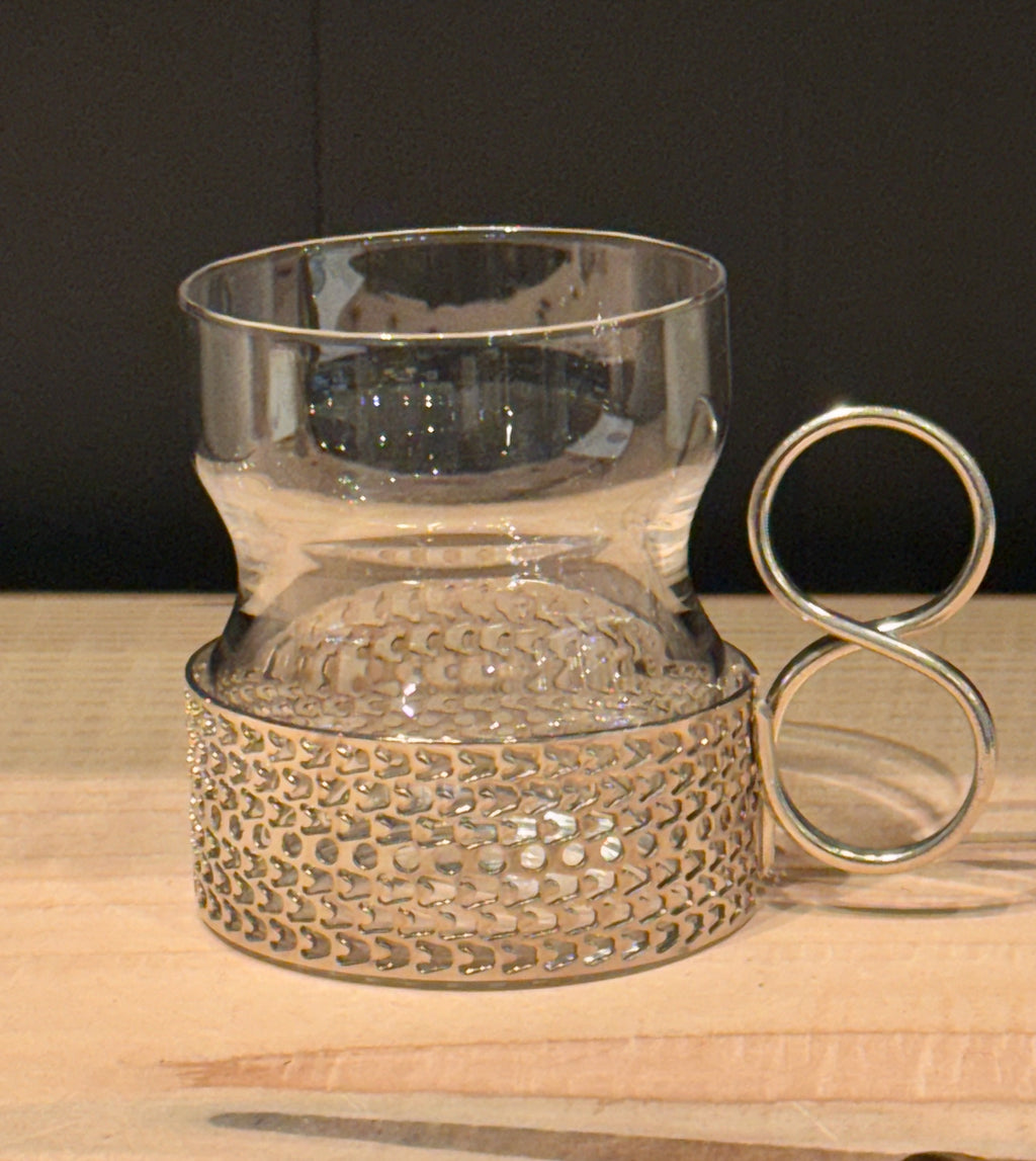 Decorative glass holder with metallic base on a wooden surface