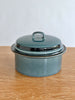 Teal enameled cast iron roaster with lid on a wooden surface