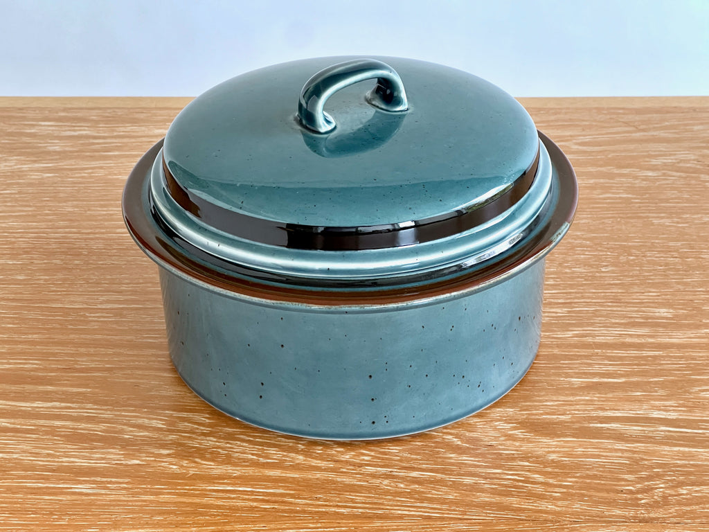 Teal ceramic pot with lid on a wooden surface