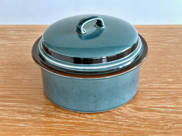 Teal ceramic pot with lid on a wooden surface
