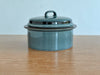 Teal ceramic container with lid on a wooden surface