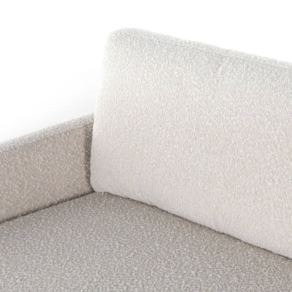 Close-up of a textured gray sofa corner with a white pillow.