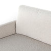Close-up of a textured gray sofa corner with a white pillow.