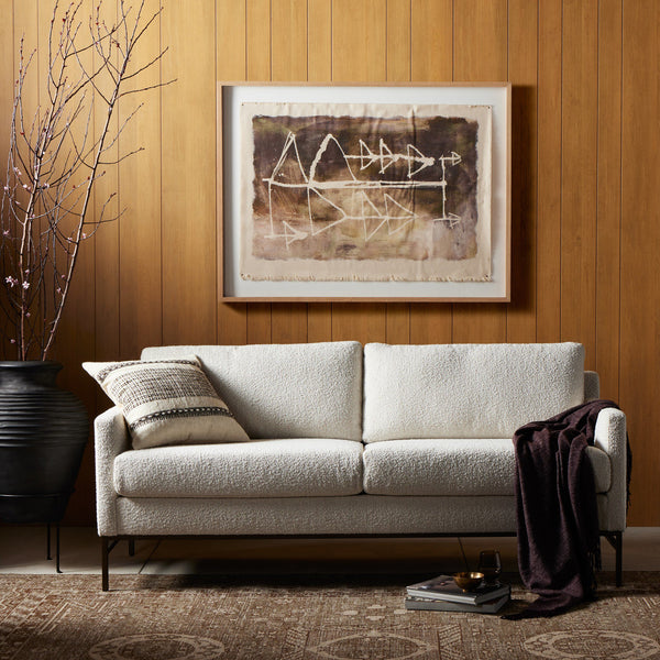 White sofa in a living room with a framed abstract painting on the wall.