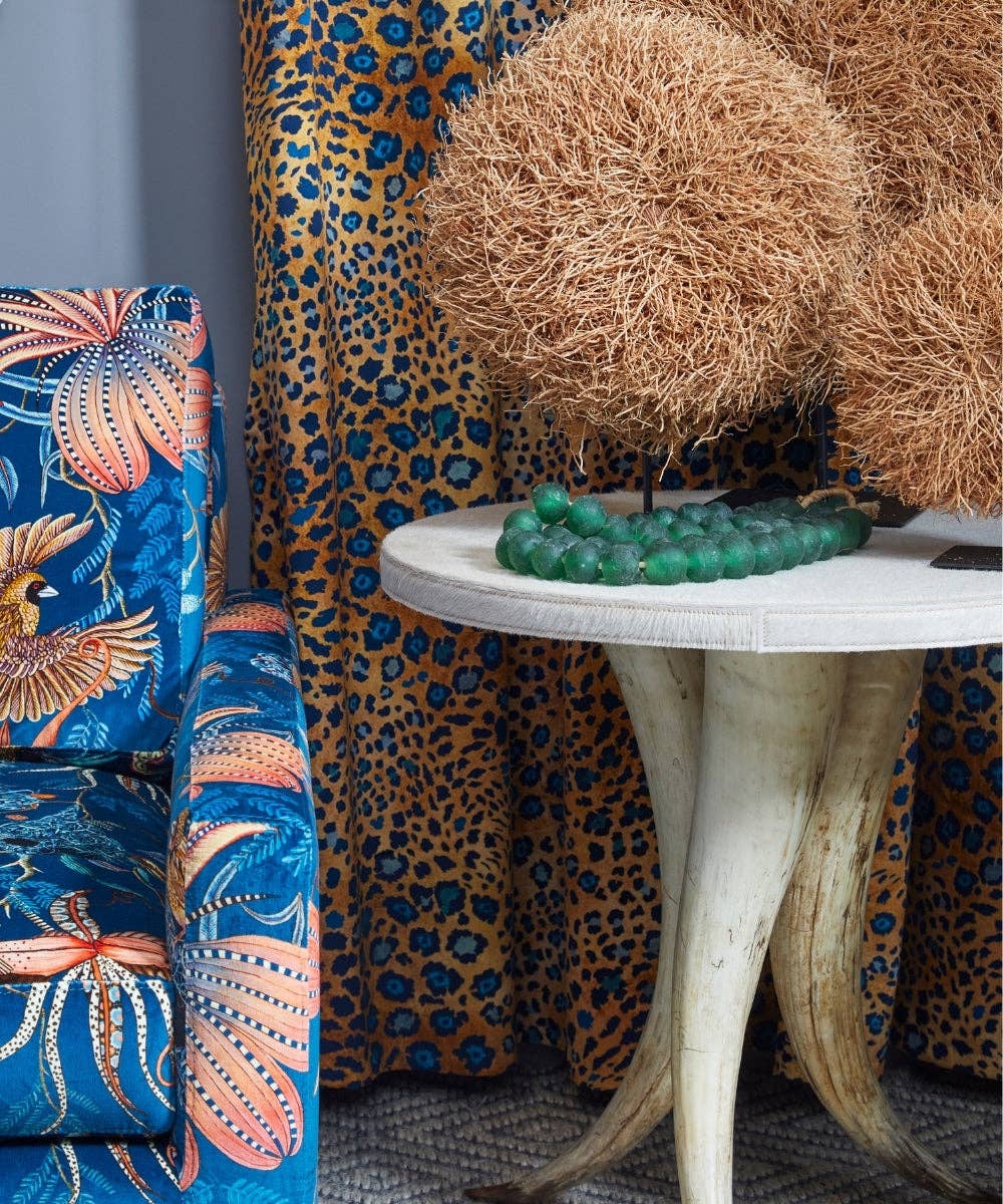 Decorative room setting with a blue patterned chair, textured wall, and round table with decorative items.