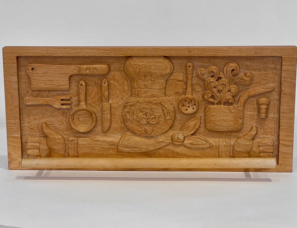 Wooden relief sculpture of a chef and kitchen utensils on a white background