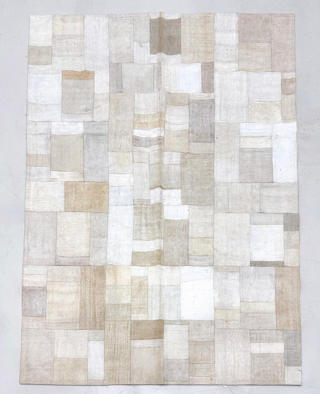 Patchwork rug with beige and brown squares on a light gray background