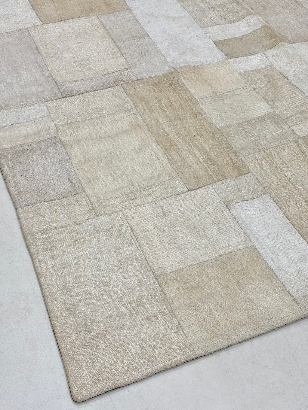 Textured area rug with a patchwork pattern on a light gray background