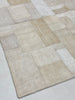 Textured area rug with a patchwork pattern on a light gray background