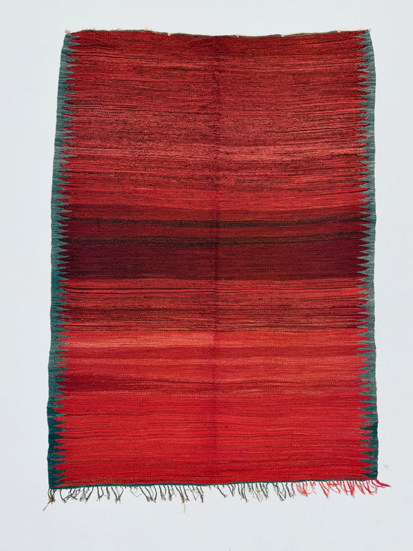 Red and green woven rug on a white background