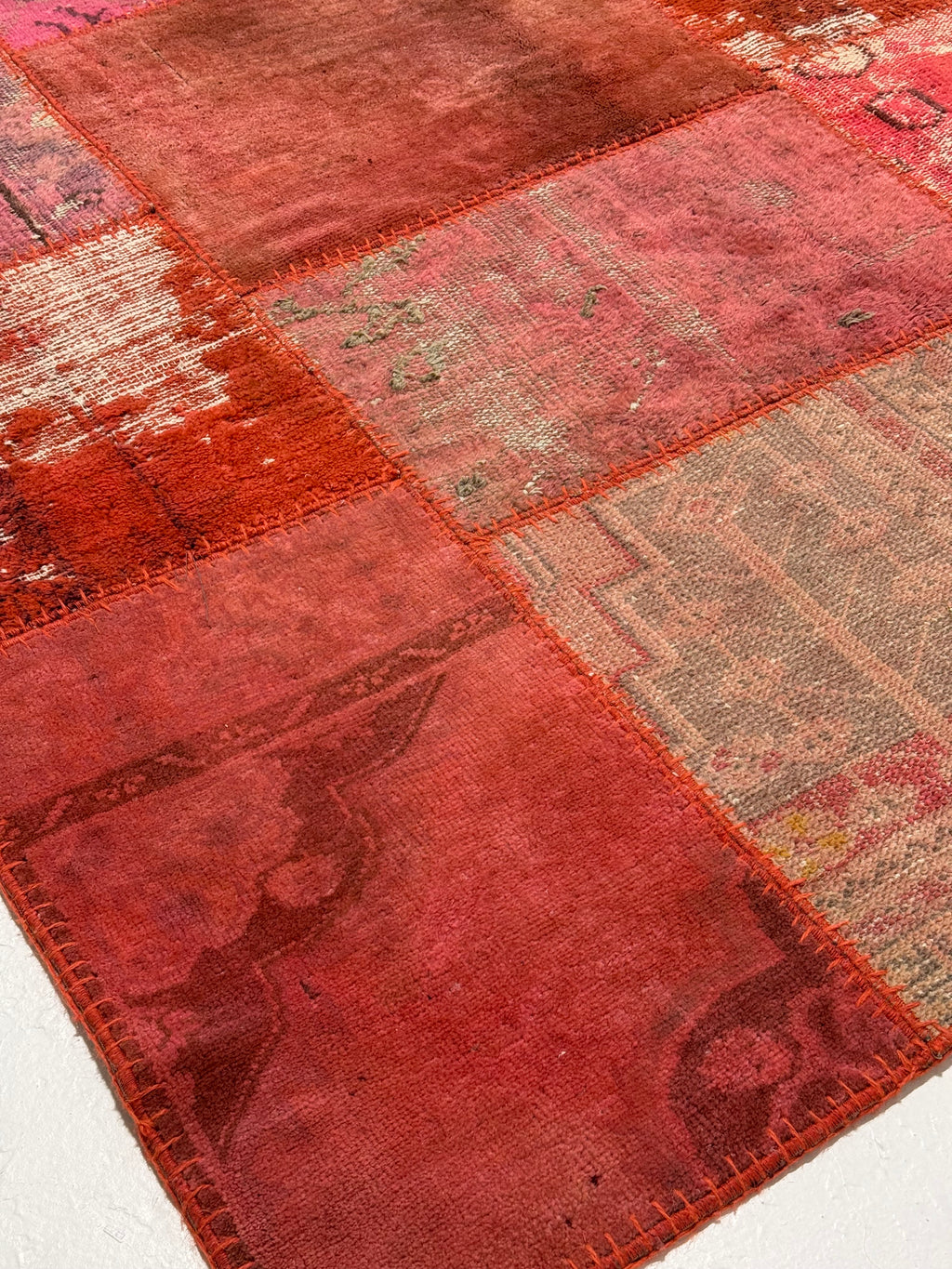 Patchwork rug with red and brown hues on a white background