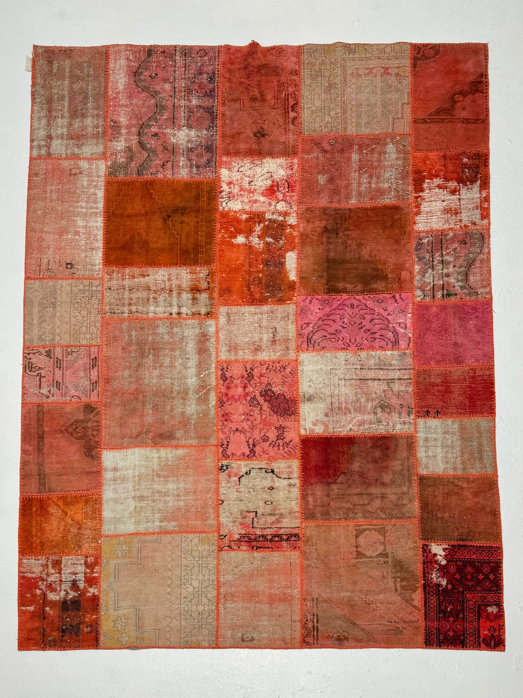 Patchwork rug with various shades of red and brown on a white background