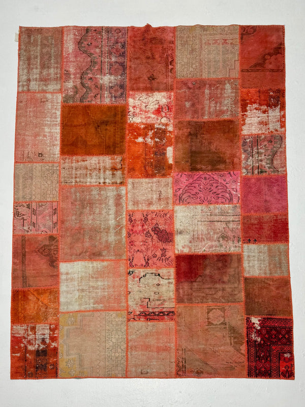 Patchwork rug with various shades of red and brown on a white background