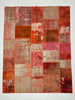 Patchwork rug with various shades of red and brown on a white background