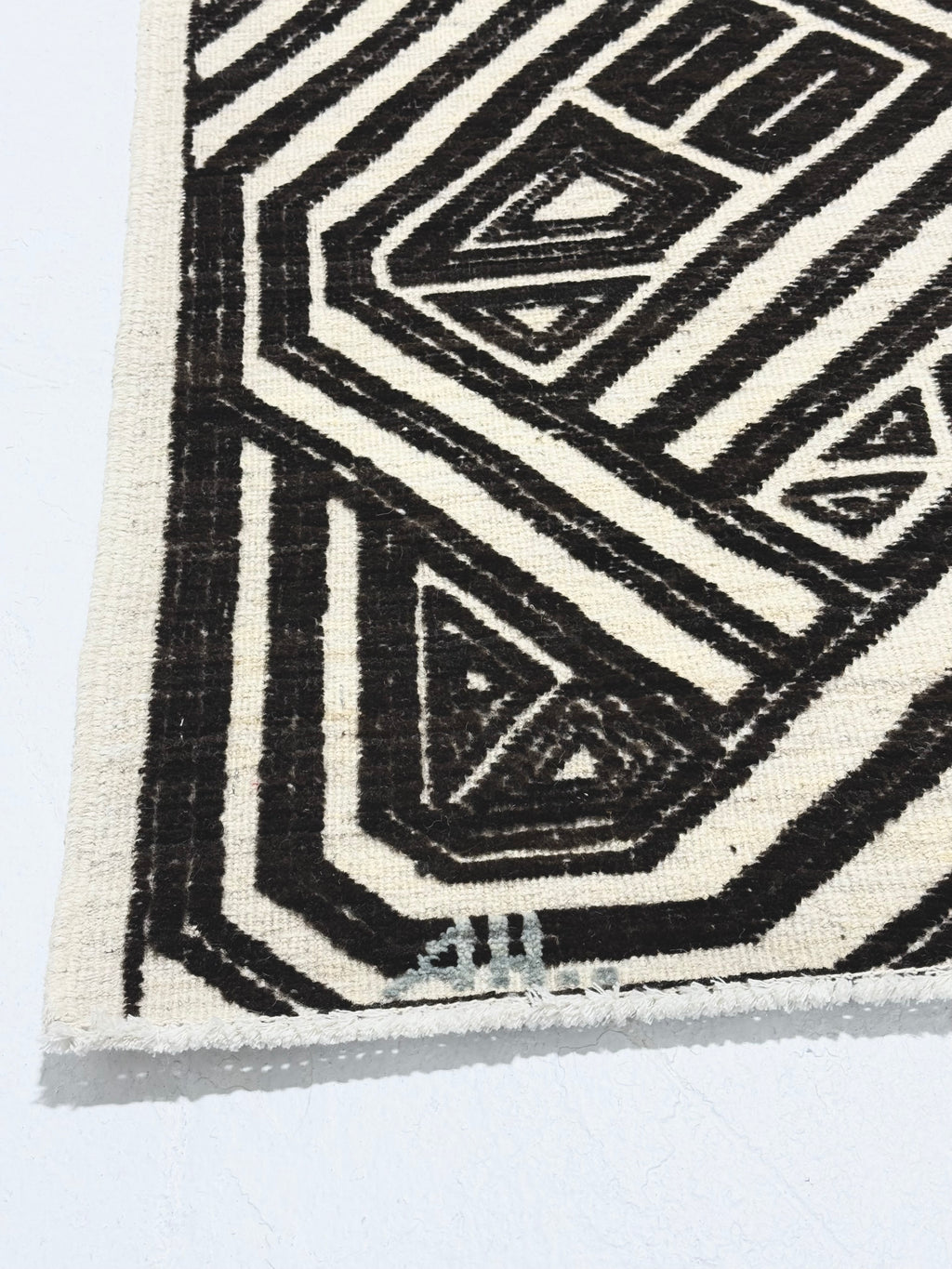 Close-up of a black and white geometric patterned rug on a light gray background