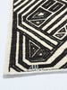 Close-up of a black and white geometric patterned rug on a light gray background