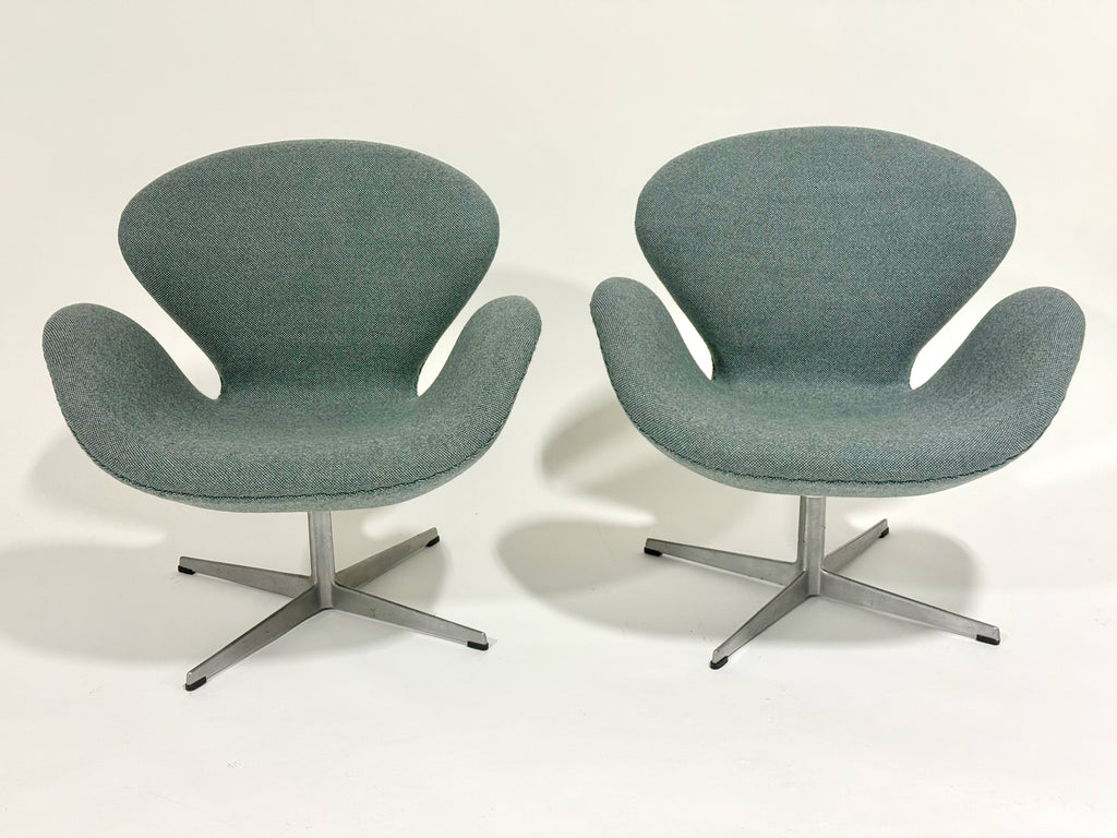 Two modern chairs with a light gray fabric and metal bases on a white background