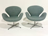 Two modern chairs with a light gray fabric and metal bases on a white background