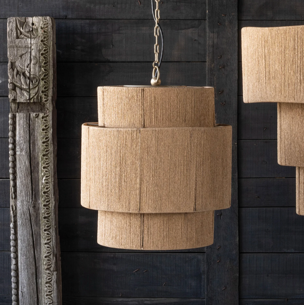 Beige pendant light hanging against a dark wooden wall.