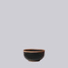 Black ceramic bowl with brown rim on a light gray background