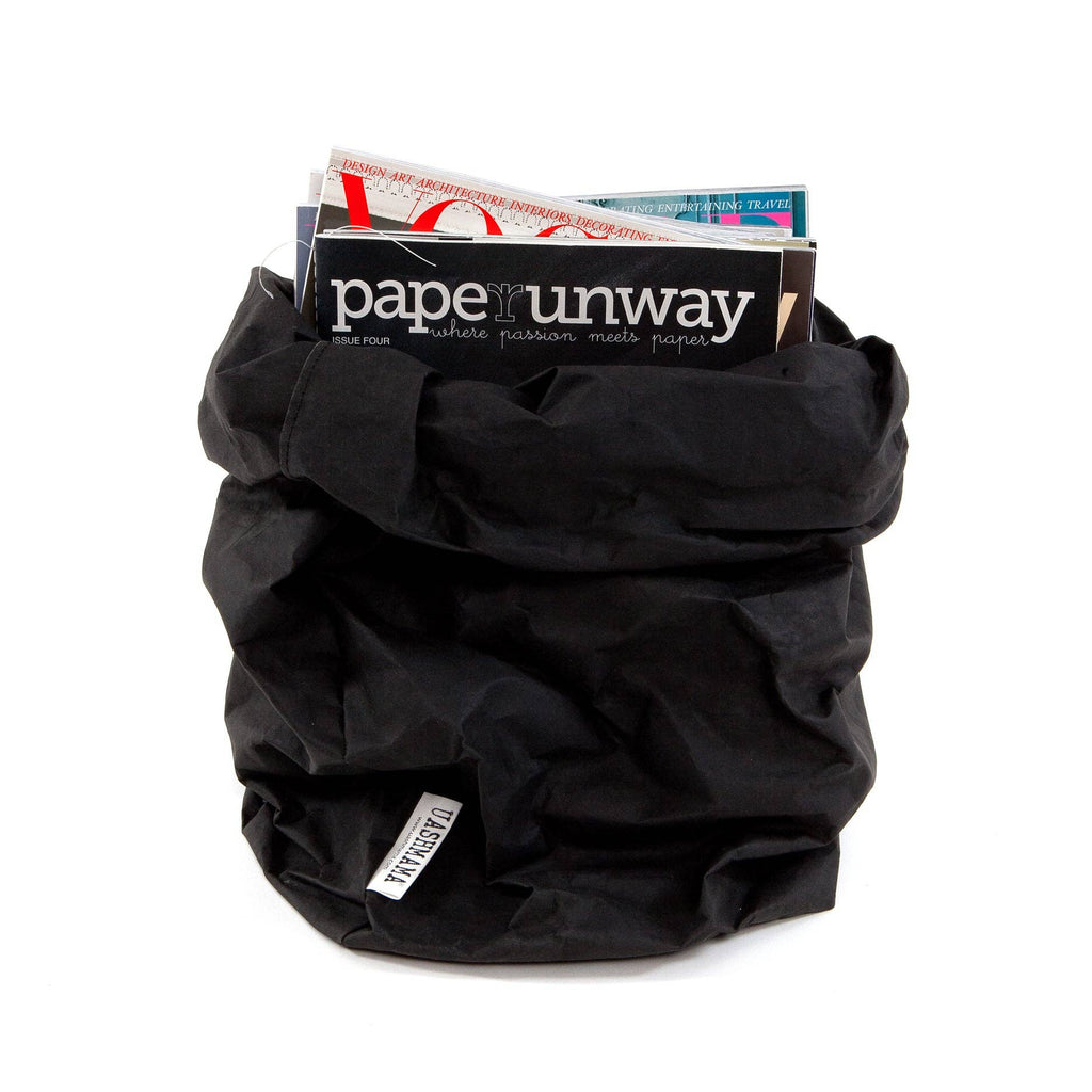 Black paper bag with a stack of magazines on a white background