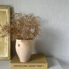 Small vase with dried flowers on a box labeled 'Horticultural Colour Chart I' against a plain wall.