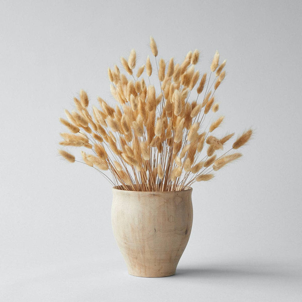 Wooden vase with dried beige flowers on a light gray background