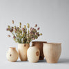 Set of wooden vases with a bouquet of dried flowers on a light gray background