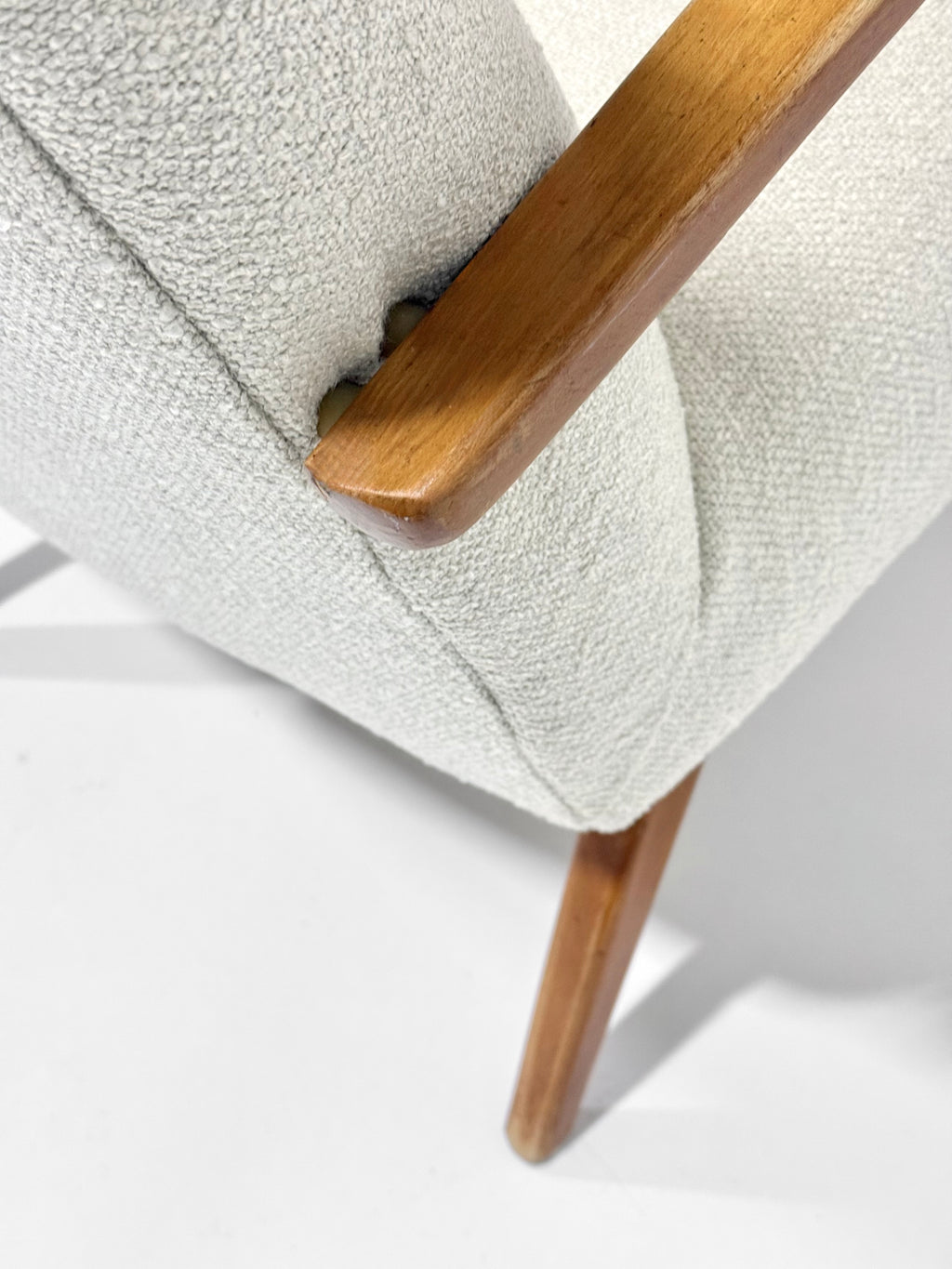 Close-up of a chair with wooden armrest and legs on a light background