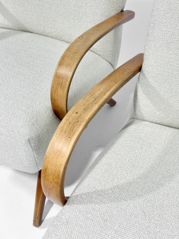 Close-up of a chair with wooden armrests and light gray cushioned backrest.