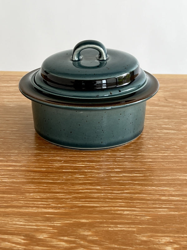 Green ceramic terrine with lid on a wooden surface