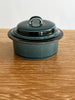 Green ceramic terrine with lid on a wooden surface