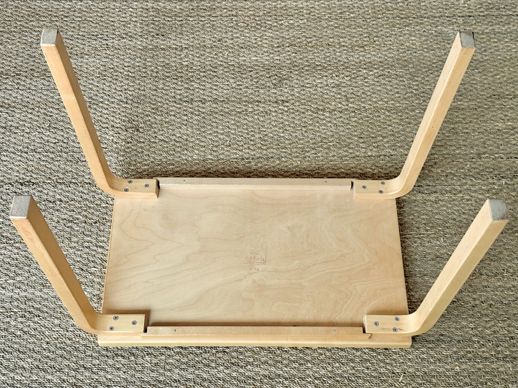 Wooden stool with four legs on a textured surface