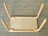 Wooden stool with four legs on a textured surface