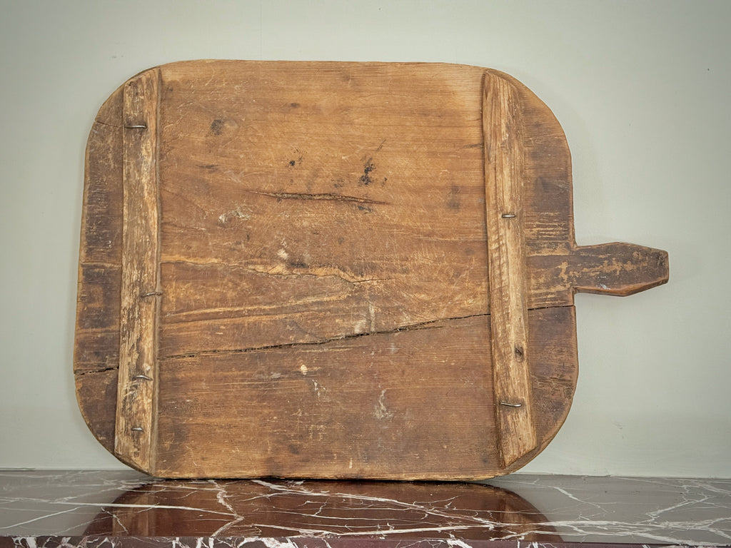 Old wooden cutting board with a handle on a gray surface